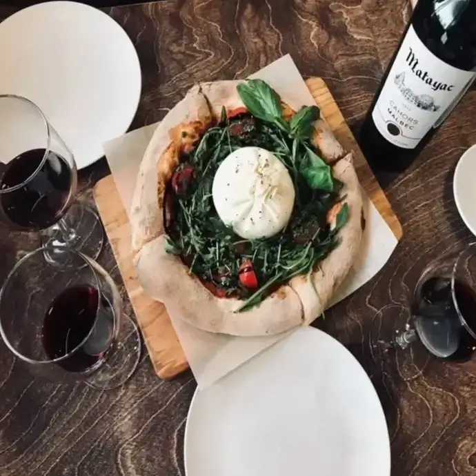 Overhead shot of burrata pizza with red wine, promoting food hygiene and safety.