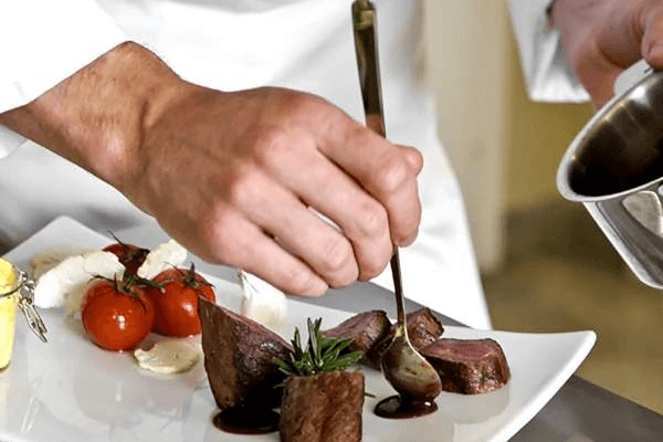 Chef plating up food for in a restaurant kitchen
